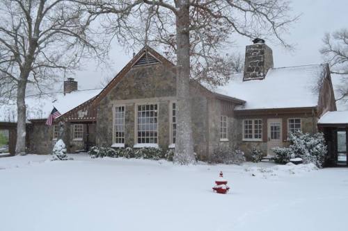 A stone house covered in snow, with an American flag and a small fire hydrant in the front yard.
