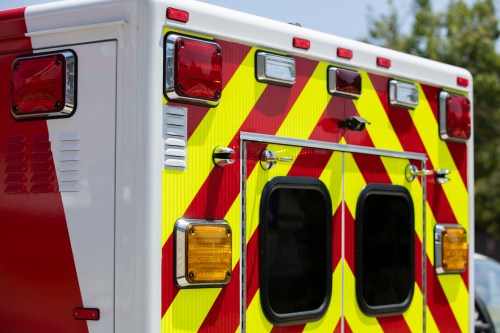 Close-up of an ambulance's rear, featuring bright red and yellow chevron patterns and emergency lights.