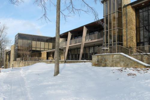 Modern building with large glass windows, surrounded by snow-covered ground and trees.