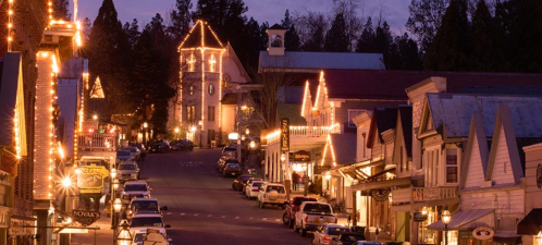 A charming street lined with historic buildings and festive lights at dusk, creating a warm, inviting atmosphere.