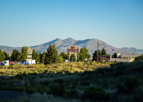 A casino sign stands in the foreground with mountains in the background under a clear blue sky.