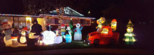 A festive display of inflatable holiday characters, including snowmen, elves, and a red car, illuminated at night.