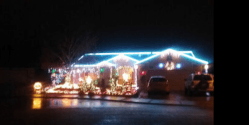 A house decorated with colorful Christmas lights, glowing brightly against a dark night sky.