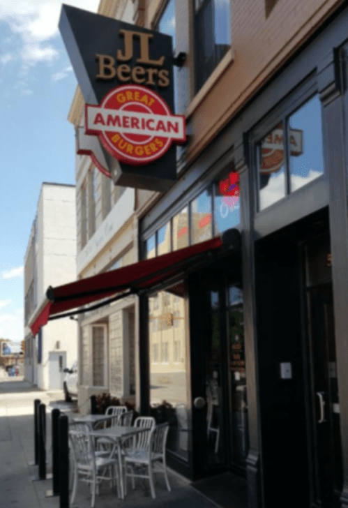 Exterior of JL Beers restaurant featuring a sign, outdoor seating, and large windows on a sunny day.