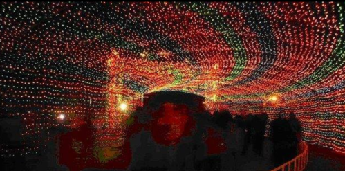 A vibrant tunnel of colorful lights with people walking through, creating a festive and enchanting atmosphere.