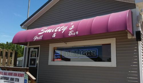 Exterior of Smitty's Grill & Bar featuring a purple awning and a Bud Light sign in the window.