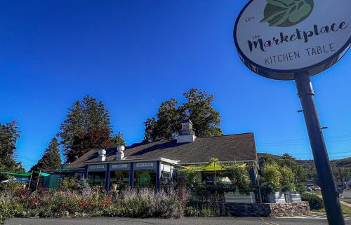 A restaurant building with a sign reading "the Marketplace Kitchen Table" under a clear blue sky.