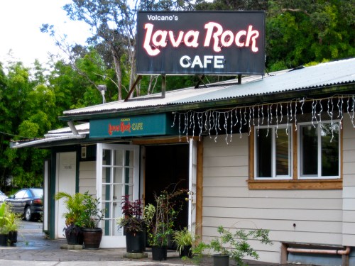 Exterior of Lava Rock Cafe with a sign, plants, and a welcoming entrance in a lush, green setting.