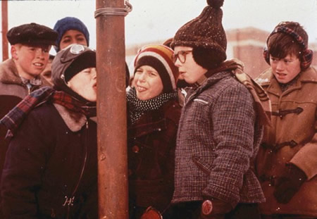 A group of children in winter clothing gathered around a pole, laughing and interacting in a snowy setting.