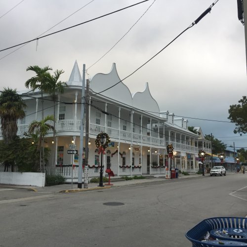 A street view of a charming building decorated for the holidays, with palm trees and a clear sky in the background.