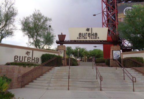 Entrance to Eureka Casino Resort, featuring stairs and signage against a backdrop of trees and a cloudy sky.
