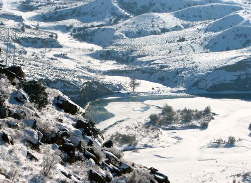 Snow-covered hills and a winding river are visible in a serene winter landscape.