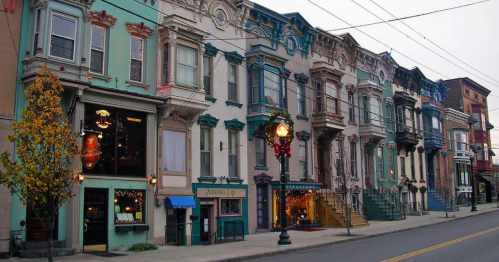 Colorful row of historic buildings with ornate facades, featuring shops and decorative details along a quiet street.