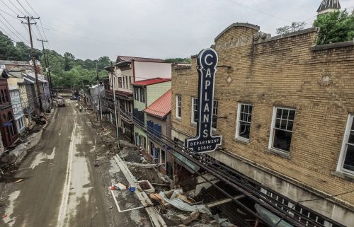 A view of a damaged street with Caplan's Department Store sign, showing debris and destruction after a disaster.