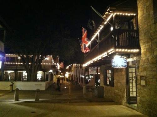 A charming, illuminated street at night with flags and festive lights adorning the buildings.