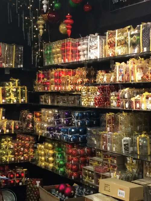 A colorful display of holiday ornaments and decorations neatly arranged on shelves in a festive store.