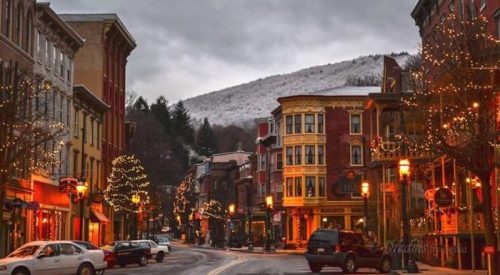 A charming street lined with festive lights and snow-capped mountains in the background, creating a cozy winter atmosphere.
