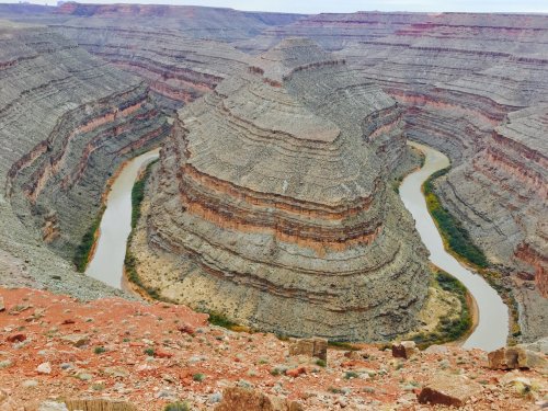A winding river flows through layered rock formations in a canyon landscape, showcasing natural erosion and geological features.