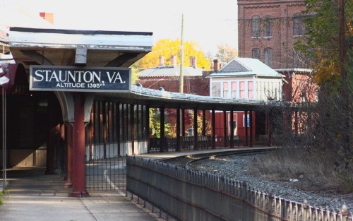 A train station in Staunton, Virginia, featuring a covered platform and nearby historic buildings.