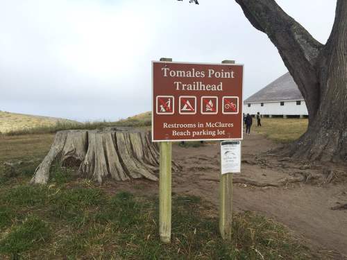 Sign at Tomales Point Trailhead indicating restrooms and trail activities like hiking and biking.