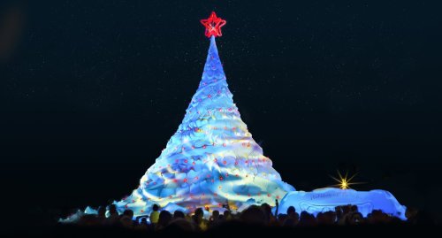 A brightly lit, large Christmas tree with a star on top, surrounded by a festive crowd under a starry night sky.