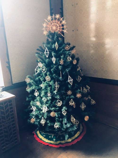 A decorated Christmas tree with geometric ornaments and a star on top, set against a wooden background.