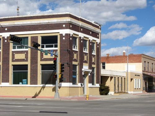 A brick building at a street corner with traffic lights and a clear blue sky in the background.