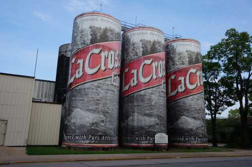 Three large silos with La Crosse branding, featuring a scenic design, set against a clear blue sky.