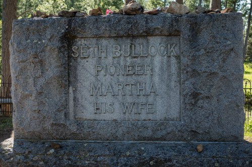 A weathered stone grave marker inscribed with "Seth Bullock Pioneer" and "Martha His Wife," surrounded by rocks.