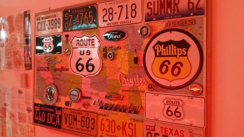 A colorful collage of Route 66 memorabilia, including maps, license plates, and vintage car logos on a wall.