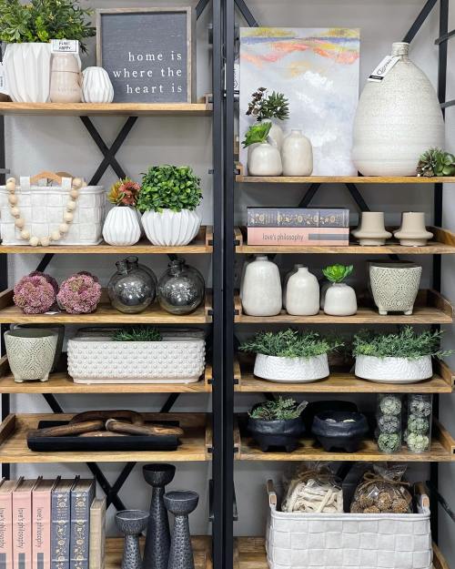 A stylish shelf display featuring decorative vases, plants, books, and various home decor items in neutral tones.