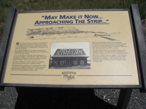 Sign describing the history of the Canyon Airport, with mountains in the background. Text highlights its significance.