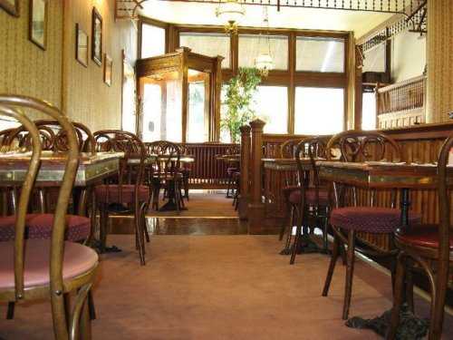 Interior of a cozy restaurant featuring wooden tables, chairs, and a warm, inviting atmosphere.
