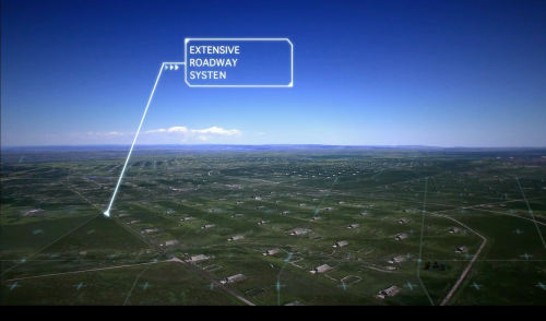 Aerial view of a vast landscape with a highlighted extensive roadway system in the distance.