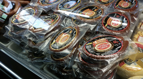 A display of packaged cheese products, featuring various flavors and brands, arranged neatly in a cooler.
