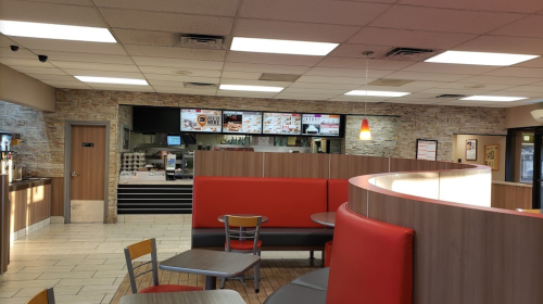 Interior of a fast-food restaurant featuring red seating, a counter with menus, and a modern design.