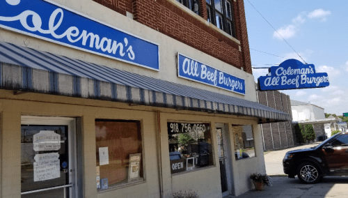 Exterior of Coleman's All Beef Burgers, featuring a blue awning and signage, with a parked car in front.