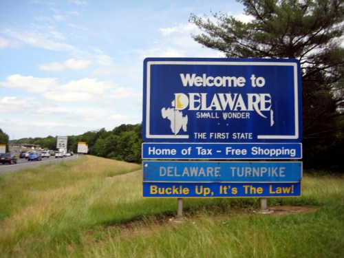 Welcome sign for Delaware, highlighting tax-free shopping and the Delaware Turnpike, with a reminder to buckle up.