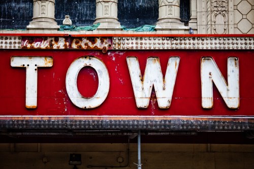 Close-up of a vintage theater marquee sign with the word "TOWN" in large, weathered letters against a red background.