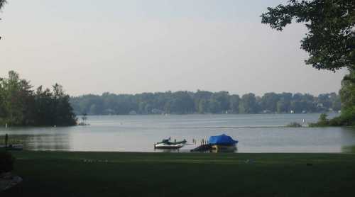 A serene lake view with boats on the water, surrounded by trees and a calm atmosphere.