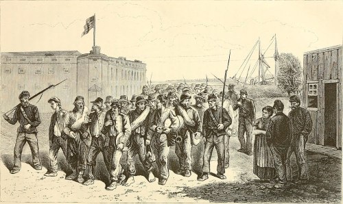 Civil War soldiers and prisoners march past a fort, with ships in the background and civilians observing.