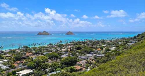 A scenic view of a coastal landscape with turquoise waters, palm trees, and two small islands in the distance.