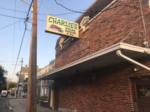Exterior of Charlie's Steak House & Bar, featuring a brick facade and a sign, on a quiet street at dusk.