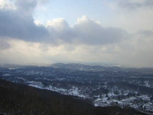 A panoramic view of snow-covered hills and valleys under a cloudy sky.
