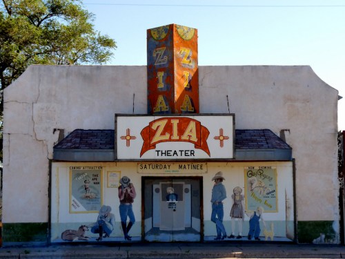 A vintage theater building with a colorful mural, featuring the name "ZIA THEATER" and a Saturday matinee sign.