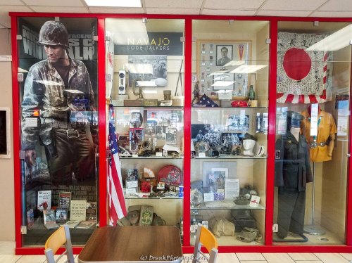 Display case featuring military memorabilia, including Navajo Code Talker artifacts and historical items.