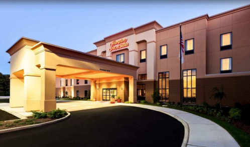 Exterior view of a Hampton Inn hotel at dusk, featuring a welcoming entrance and landscaped surroundings.