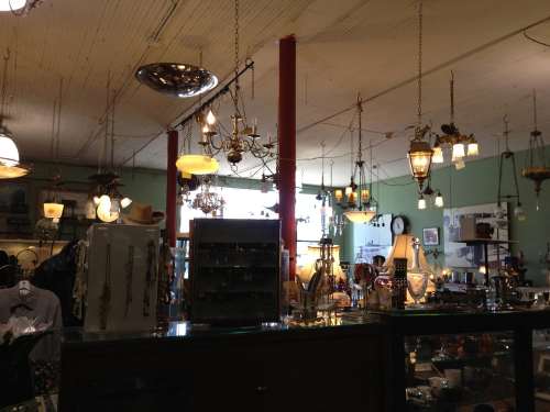 A vintage shop filled with various hanging lamps and antique items, creating a warm, inviting atmosphere.