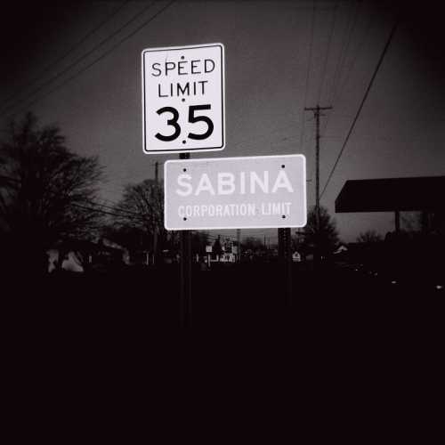 A black and white image of two road signs: one indicating a speed limit of 3.5 and the other marking the town of Sabina.