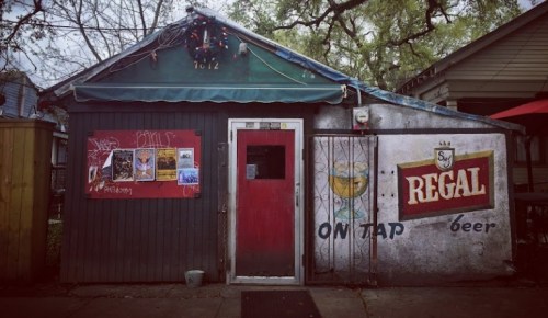 A rustic building with a red door, festive decorations, and a mural advertising beer on the side.